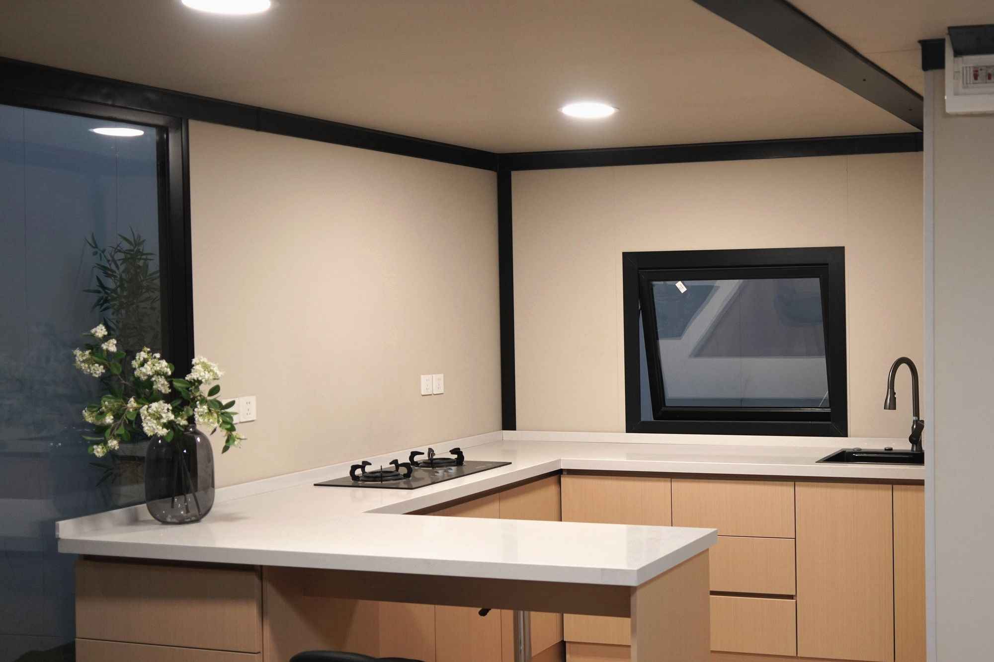 Inside a finished module: a kitchen along one wall with a breakfast bar, and a bathroom through a glazed door beyond.